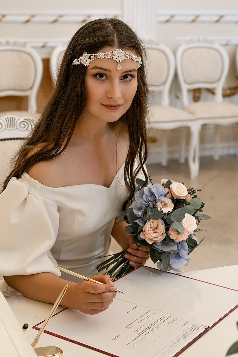 Elegant bride in diadem signing papers in registry office